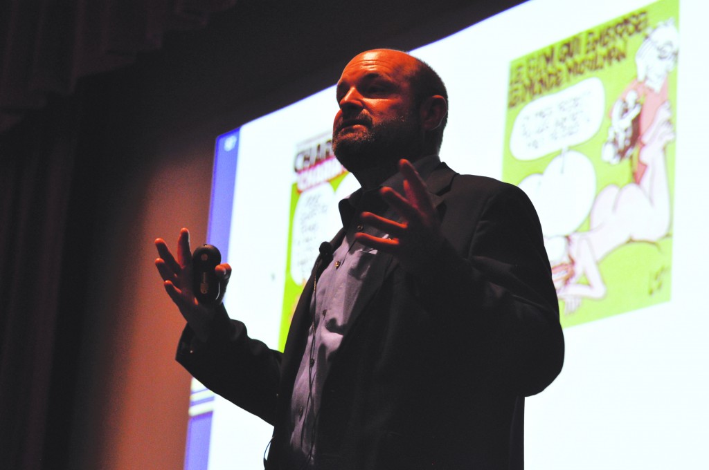 Mike Hiestand with the Charlie Hebdo illustration behind him. Photo by Giovanni Roverso