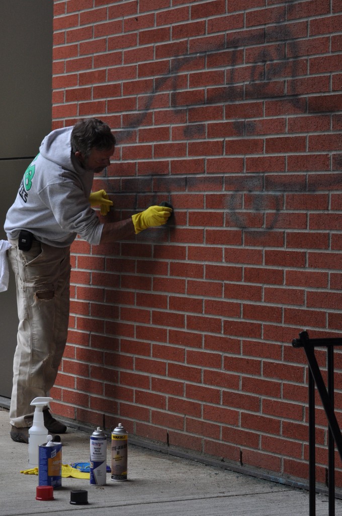 PC Support Service Staff Mike Edwards cleaning graffiti off of Maier Hall. Photo by Eric Trent
