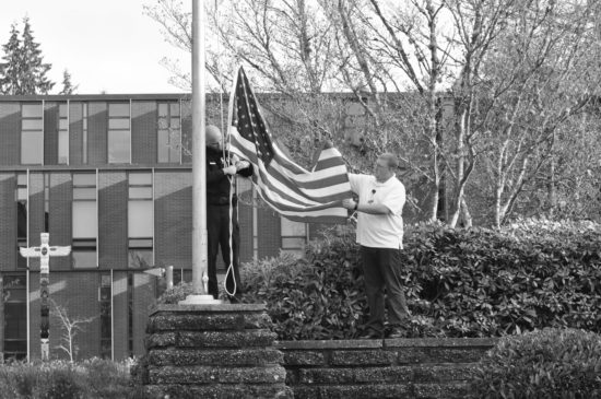 Alec Risk and Jerrod Brown pull down the old flag for retirement. - Photos by Mike Drake