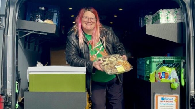 A Port Angeles Food Bank employee handing food out to Peninsula College students